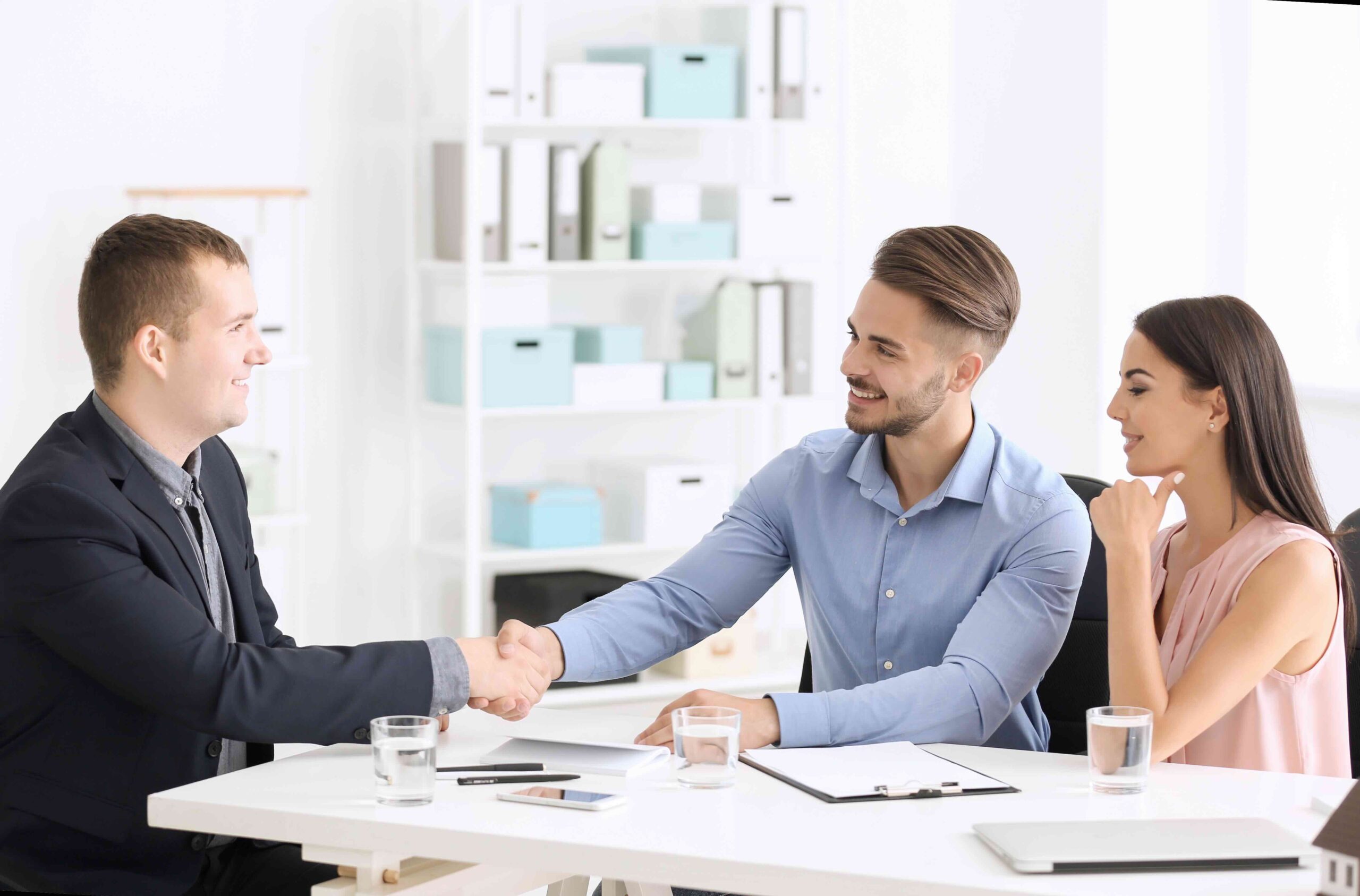 Young man shaking hands with estate agent in office